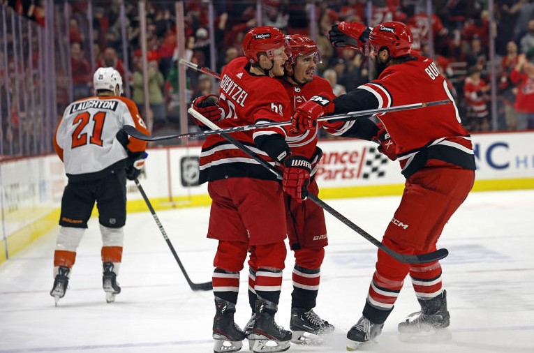 Carolina Hurricanes' Seth Jarvis, center, celebrates after his winning overtime goal with teammates Brent Burns, right, and Jake Guentzel (59) as Philadelphia Flyers' Scott Laughton (21) skates past at an NHL hockey game in Raleigh, N.C., Thursday, March 21, 2024. (AP Photo/Karl B DeBlaker) © Provided by The Associated Press