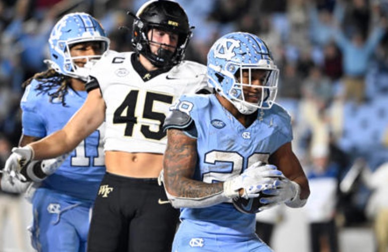 North Carolina Tar Heels running back Omarion Hampton (28) scores a touchdown as Wake Forest Demon Deacons defensive back Nick Andersen (45) defends in the fourth quarter at Kenan Memorial Stadium. Mandatory Credit: Bob Donnan-Imagn Images © Bob Donnan-Imagn Images