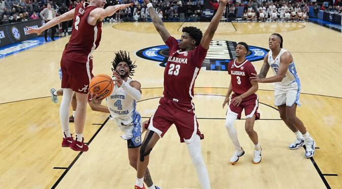 North Carolina guard RJ Davis (4) drives to the basket between Alabama forward Grant Nelson (2) and forward Nick Pringle (23) during the second half of a Sweet 16 college basketball game in the NCAA tournament Thursday, March 28, 2024, in Los Angeles. (AP Photo/Ashley Landis)